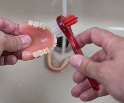 Dentures patient in Derry rinsing their prosthetic