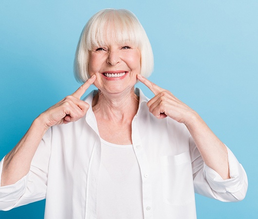 Older woman pointing to smile 